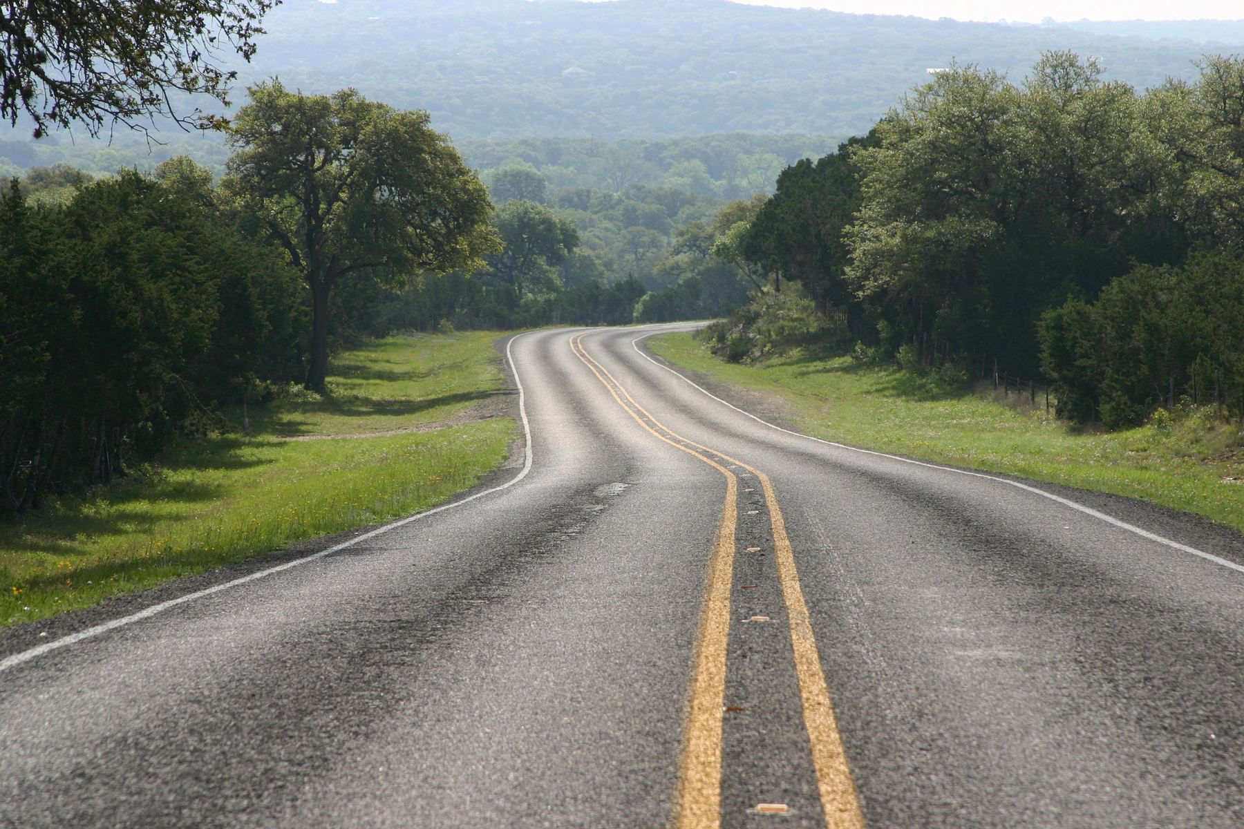 A two-lane road winding down through the Texas Hill Country