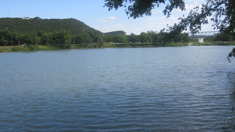 The river in Junction seen from the city park, with wooded hills and a bridge in the distance