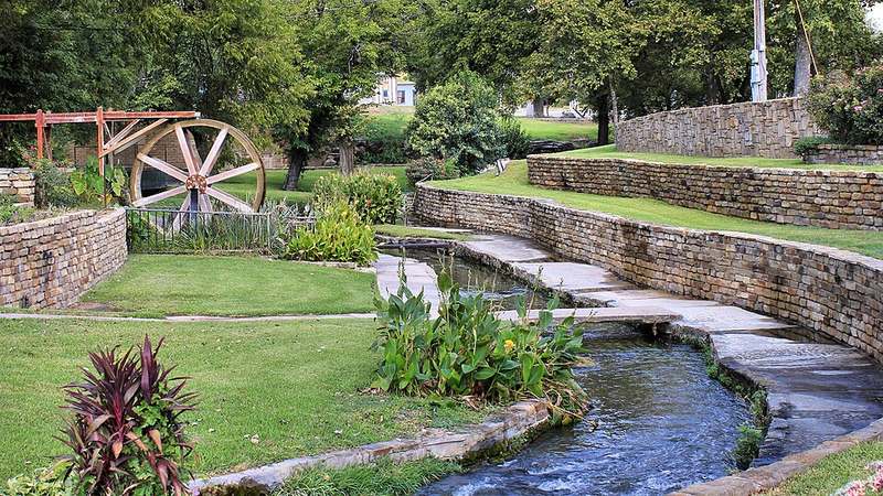 Spring water running through the stone channels and the old water wheel at Mill Pond Park, San Saba