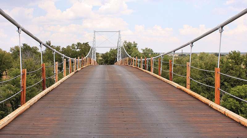 The one-lane wooden deck of the Regency Suspension Bridge over the Colorado River